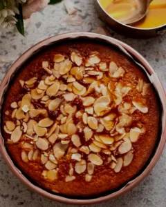Rustic honey and herb-infused cake topped with toasted almonds, drizzled with golden honey, and set against a moody, earthy backdrop with warm lighting and soft shadows.