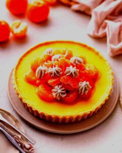 A golden-baked Sweet Blossom Tart with a honey-almond filling, lightly dusted with powdered sugar and adorned with delicate edible flowers, evoking the freshness of spring and the blessings of Eostre.