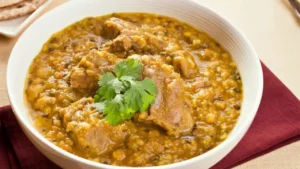 “Bowl of Parsi Dhansak – a rich, slow-cooked lentil and meat stew with golden hues, garnished with fresh coriander”